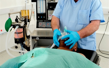 Anaesthetist fitting mask to a patient